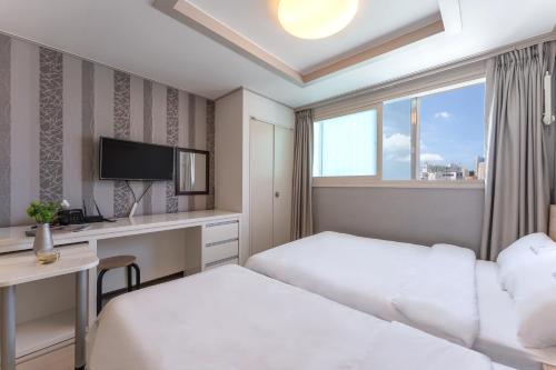 a hotel room with two beds and a desk at Staywell Hotel in Busan