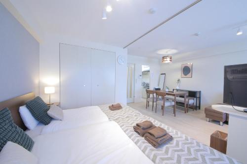 a white bedroom with a bed and a dining room at ノーザンヒルズ南6条 in Sapporo