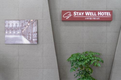 a sign on the wall of a building with a plant at Staywell Hotel in Busan