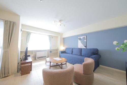 a living room with a blue couch and two chairs at ノーザンヒルズ南6条 in Sapporo