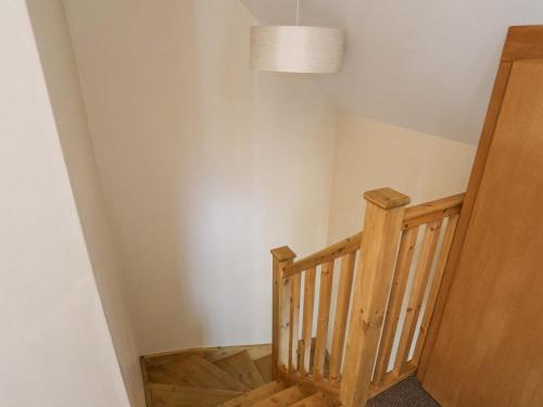 a hallway with a wooden staircase with a pendant light at Ffynnon Bach in Caernarfon