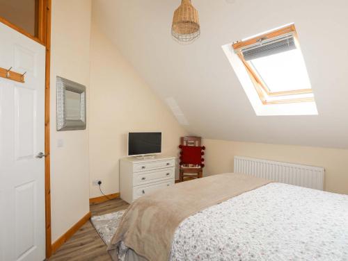 a bedroom with a bed and a tv and a window at Ffynnon Bach in Caernarfon