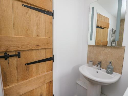 a bathroom with a white sink and a wooden door at Fisherman's Cottage in Llandysul