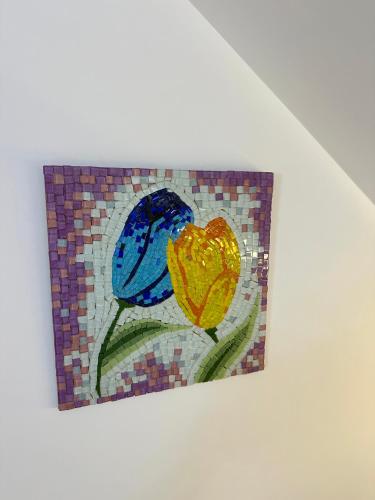 a mosaic picture of two flowers on a wall at BlackMountain Hotel in Kolgecaj