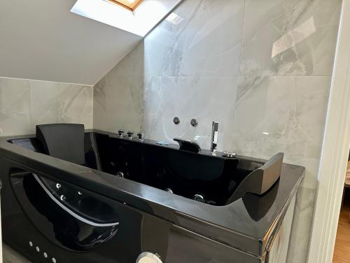 a bathroom with a black tub and a sink at BlackMountain Hotel in Kolgecaj