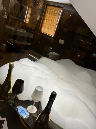 two bottles of wine sitting on a bed with snow at BlackMountain Hotel in Kolgecaj