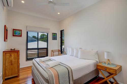 Un dormitorio blanco con una cama y una ventana. en Frangipani Place - Absolute Beachfront, en South Mission Beach