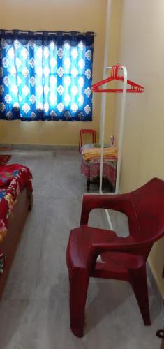 a red chair in a room with a window at Two BHK Fully Furnished Flat - Near Charminar and Salar Jung Museum in Hyderabad