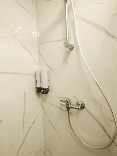 a shower in a bathroom with a hose on the wall at Cozy Noko Apartments in Kaunas