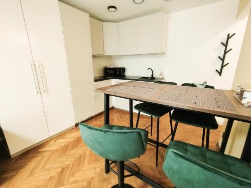 カウナスにあるCozy Noko Apartmentsの木製のテーブルと緑の椅子のあるキッチン