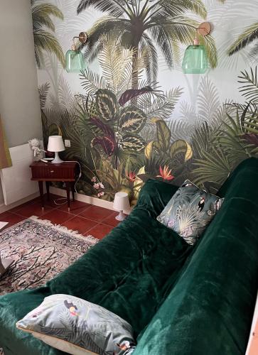 - un canapé vert avec des oreillers dans le salon dans l'établissement Gîte de standing climatisé avec piscine, à Sainte-Cécile-les-Vignes