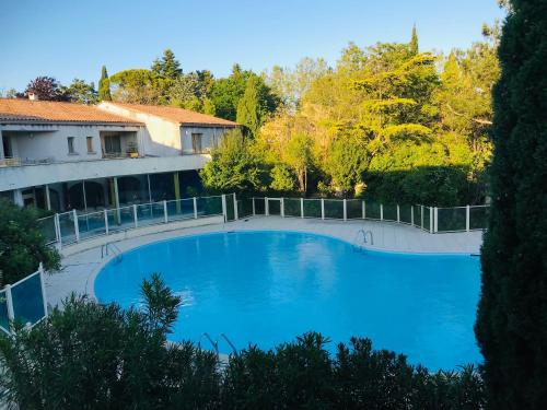 une grande piscine bleue à côté d'un immeuble dans l'établissement Gîte de standing climatisé avec piscine, à Sainte-Cécile-les-Vignes