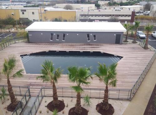 une grande piscine dans un parking avec des palmiers dans l'établissement Studio meublé, à Saint-Jean-de-Védas