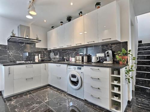 une cuisine avec des armoires blanches et une machine à laver dans l'établissement Maison Lumineuse et Moderne Paris Disney, à Montfermeil