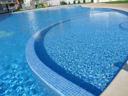 a large blue swimming pool with blue water at Alojamentos Campo & Mar-T2 com Piscina in São Martinho do Porto