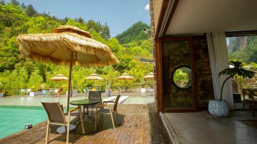 a patio with a table and chairs and an umbrella at Pandora Vista Retreat in Zhangjiajie