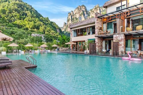 a hotel swimming pool with mountains in the background at Pandora Vista Retreat in Zhangjiajie