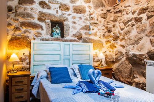 a bedroom with a bed with blue pillows and a stone wall at La Cuadra in Villar de Corneja
