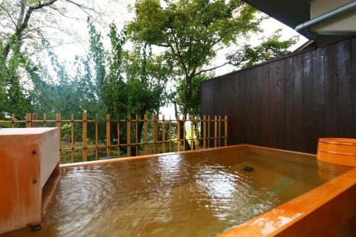 a patio with a hot tub and a wooden fence at Kafutei in Yamaga