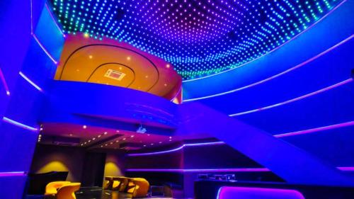 a room with purple and blue lights on the ceiling at The Weekend Address Managed By Stay Cation in Surat