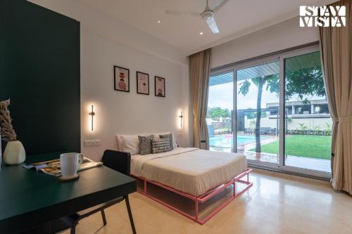a bedroom with a bed and a desk and a window at StayVista at Gulposh Retreat with Pool, Lawn & Gazebo in Karjat