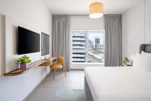 a hotel room with a bed and a desk and a window at Citadines Metro Central Dubai in Dubai