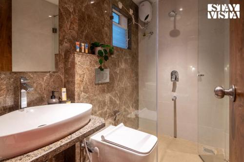 a bathroom with a sink and a toilet and a shower at StayVista at Gulposh Retreat with Pool, Lawn & Gazebo in Karjat
