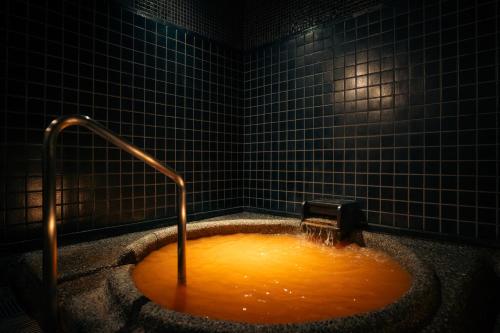 a bath tub filled with orange water with a faucet at Hotel Hanakoyado in Kobe