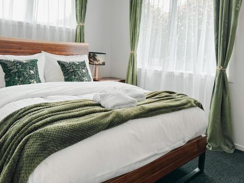 a bedroom with a white bed with a green blanket at Two One Two in Hokitika
