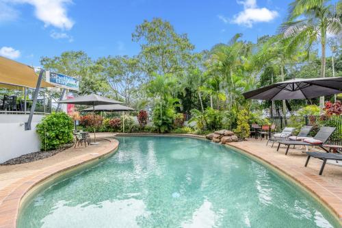 a pool with chairs and umbrellas in a yard at Shelly Bay Resort in Hervey Bay