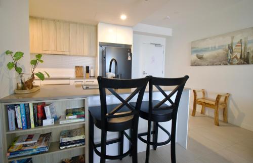 a kitchen with two black chairs and a kitchen table at Maroochy City Lights@Thecosmopolitan Unit 20802 in Maroochydore