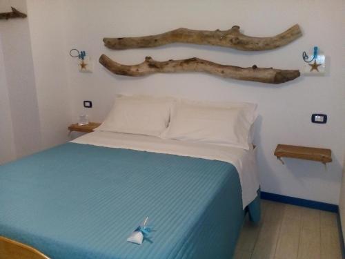 a bedroom with a bed with a branch on the wall at ControVento Rooms in Margherita di Savoia