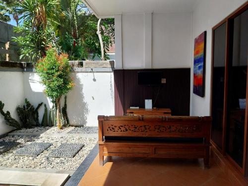 a wooden bench in a room with a tv at Umah Kita in Seminyak