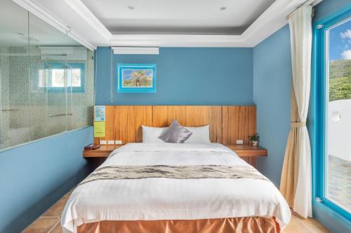 a blue bedroom with a bed and a window at Kenting Shen's Homestay in Eluan