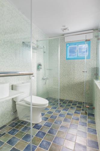 a bathroom with a toilet and a glass shower at Kenting Shen's Homestay in Eluan