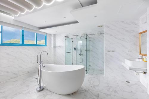 a white bathroom with a tub and a glass shower at Kenting Shen's Homestay in Eluan