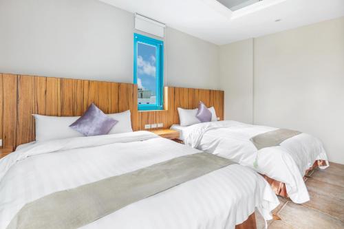 a bedroom with two beds with white sheets and purple pillows at Kenting Shen's Homestay in Eluan