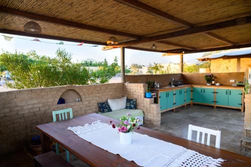 a patio with a wooden table and a kitchen at ביתהבוצ - מקום טבעי למפגשים in Talmei Yosef