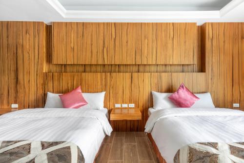 two beds in a room with wooden walls at Kenting Shen's Homestay in Eluan