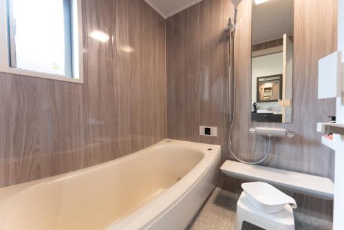 a bathroom with a tub and a toilet and a sink at Villa Ray Miyakojima in Hirara