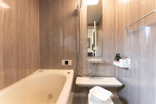 a bathroom with a tub and a toilet and a sink at Villa Ray Miyakojima in Hirara