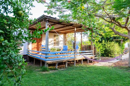 a tiny house with a porch and blue chairs at ביתהבוצ - מקום טבעי למפגשים in Talmei Yosef