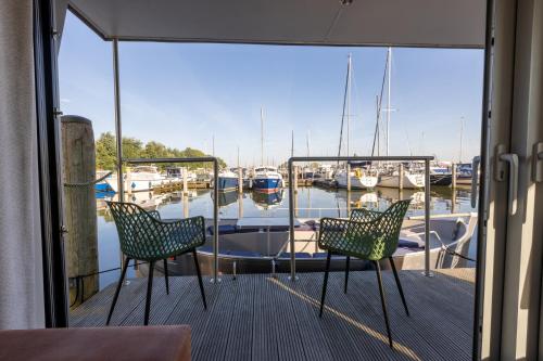 two chairs on a dock with a boat in the water at Home of the Houseboat - Zen in Dinteloord