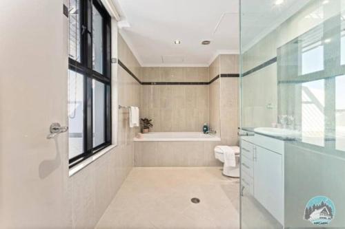 a bathroom with a tub and a toilet and a sink at Breathtaking Waterfront Penthouse with BigTerrace near to Olympic Park in Sydney