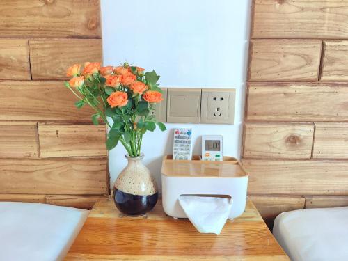 a vase with orange flowers on a table in a bedroom at Just waiting for you-Tianmen mountαin-English reception-Book ticket service in Zhangjiajie