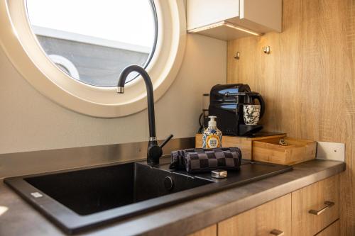 a kitchen with a sink and a window at Home of the Houseboat - Zen in Dinteloord