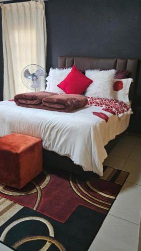 a bedroom with a bed with red and white pillows at Happy Stay Guest House Mafikeng in Mahikeng
