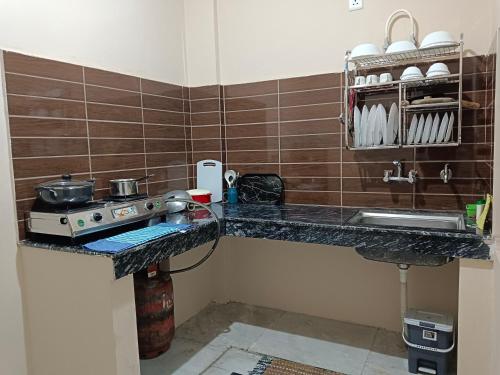 a kitchen counter with a stove and a sink at Aditya Homestay Bir-Billing surrounded by Mountains in Bīr