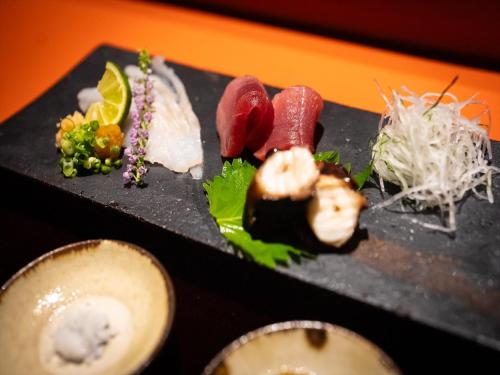 a black plate of food with sushi and vegetables at Oriental Hills Okinawa in Onna