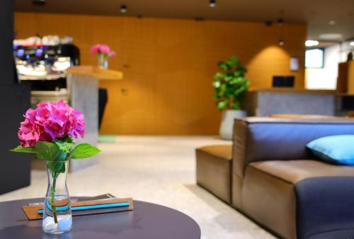 a vase with pink flowers on a table in a living room at Hotel Soča in Bovec